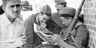 Historische Aufnahme in Schwarz/weiss. Junge Soldaten blättern in einer Zeitung