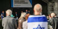 Ein Demonstrant mit israelischer Flagge verfolgt die Reden bei einer Kundgebung