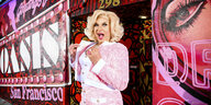 D'Arcy Drollinger in rosafarbenen Outfit vor der bemalten Fassade des Oasis Nachtclub in San Francisco