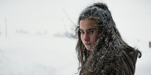 Ein Mädchen mit langen, dunklen, schneebedeckten Haaren