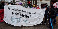 Protestierende halten einen Banner hoch, darauf steht "Spekulation bekämpfen! H48 bleibt!" und eine Abbildung einer Faust