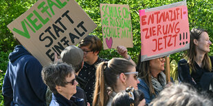 Eine Gruppe hält Plakate hoch worauf Sätze stehen wie 