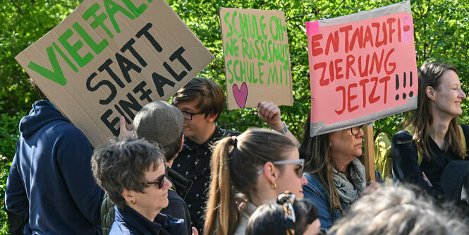 Eine Gruppe hält Plakate hoch worauf Sätze stehen wie "Vielfalt statt Einfalt" oder "Entnazifizierung jetzt!!!"