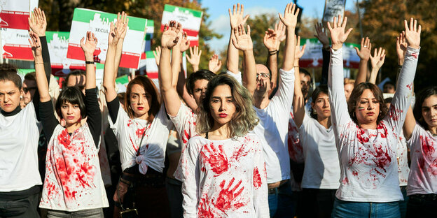 Frauen mit roten Handabdrücken auf ihren T-Shirts und Iran-Flaggen