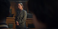 Sandra Hüller im Jackett steht mit gefalteten Händen in einem Gerichtssaal