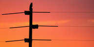 Stromleitung vor rotem Sonnenaufgang