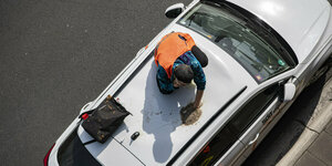 Ein Aktivist klebt auf einem Autodach