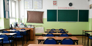 Leerer Klassenraum mit Tafel, Pult und Tischen und Stühlen