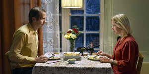 Ein Mann und eine Frau sitzen sich an einem gedeckten Tisch gegenüber und essen