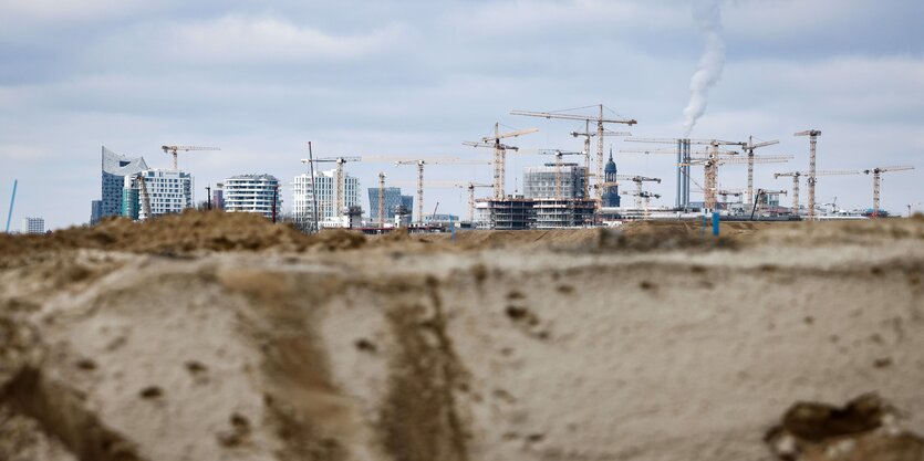 Blick auf eine Baugrube, im Hintergrund viele Kräne und die Hamburger Hafencity