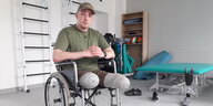 Ein junger Mann mit amputierten Beinen sitzt in einem Rollstuhl
