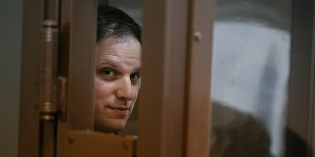 Evan Gershokovich im Glaskasten im Moskauer Gericht, er lächelt