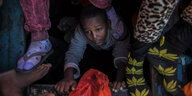 Ein Kind versucht an der Küste zu Libyen an Bord eines überfüllten Holzbootes von unten hinaufzuklettern