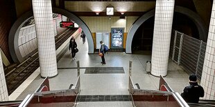 Drei Menschen stehen am Eingang vor zwei Tunnelröhren, die linke ist beleuchtet, die rechte dunkel