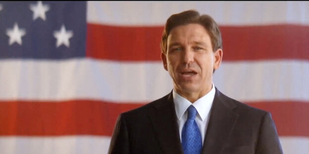 Standbild aus einem Video: Ron DeSantis vor einer US-Fahne