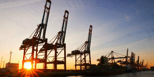 Die Sonne geht hinter Containerbrücken auf dem Terminal Eurogate im Waltershofer Hafen unter.