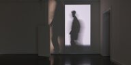Der Schatten eines Mannes an der Wand eines Ausstellungsraumes