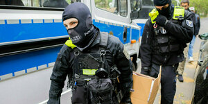 Zwei Polizisten tragen einen Karton mit beschlagnahmten Gegenständen