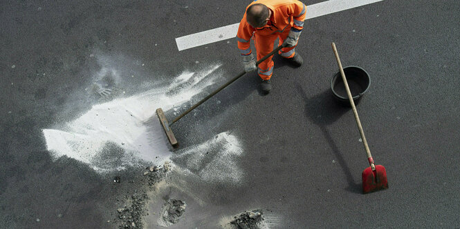 Eine Person in Arbeitskleidung bessert eine Straße aus