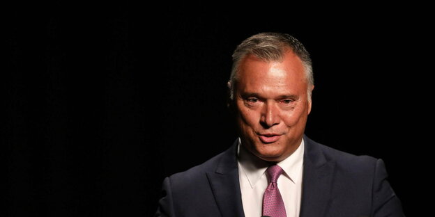 Stan Grant has short gray hair, is smiling and is wearing a suit