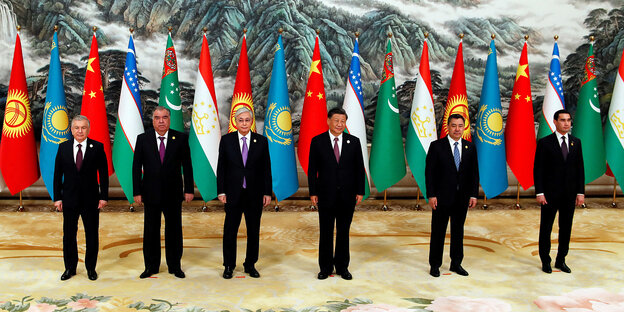 Fünf Personen vor Staatsfahnen und einem traditionellen chinesischen Gemälde