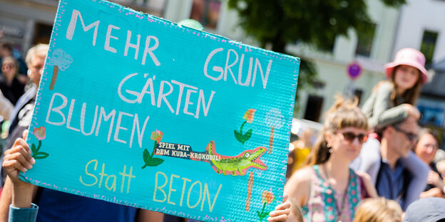 «Mehr Grün, Gärten, Blumen statt Beton» steht beim Kinderkarneval der Kulturen auf einem Schild eines Teilnehmenden am Kinderkarneval