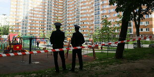 Zwei POlizisten stehen vor einem Wohnblock