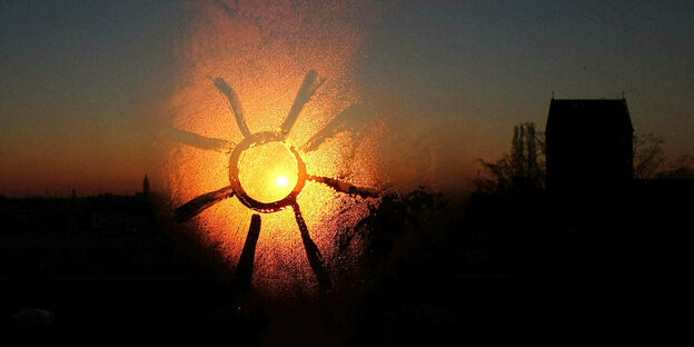 Sonne auf ein beschlagenes Fenster gemalt. Sonnenuntergang