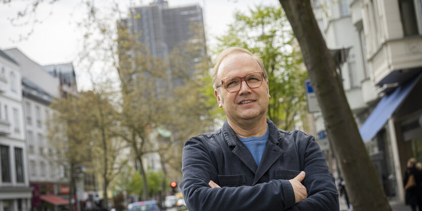 Till Raether steht mir verschränkten Armen in der Berliner Schloßstrasse, im Hintergrund der Steglitzer Kreisel