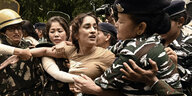 Eine indische Frau wird von Polizistinnen festgenommen