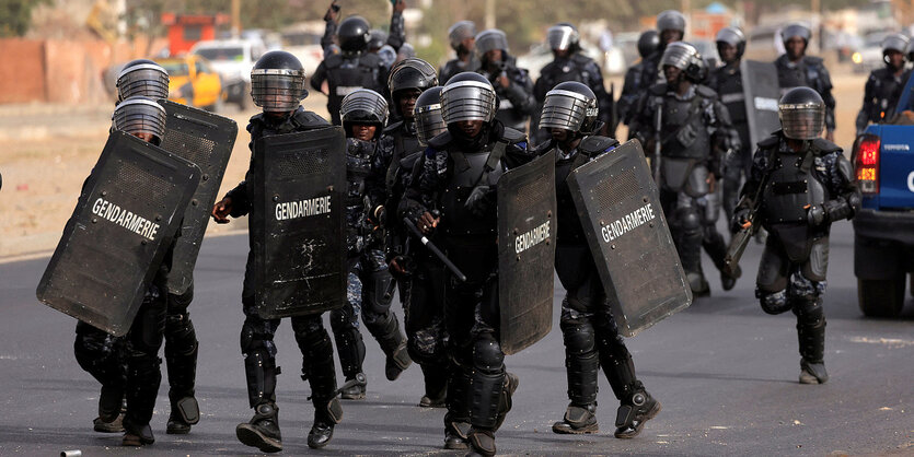 Uniformierte Polizisten mit Helmen und SChutzschildern auf den Straßen von Dakar, Senegal