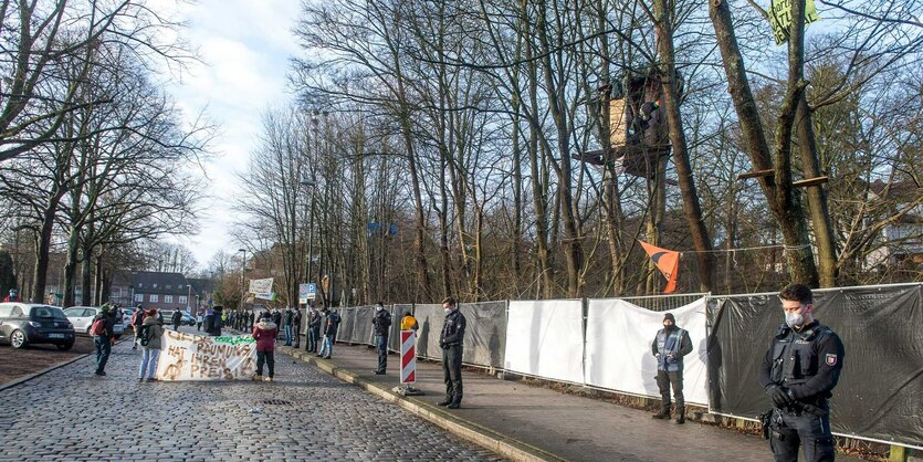 Polizisten und Demonstranten stehen vor dem abgesperrten Bahnhofswald in Flensburg