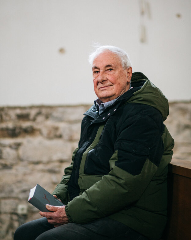Ein Mann mit Buch sitzt in einer Kirchenbank