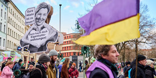 Plakat, das Giffey verspottet "Eure Miete ist zu teuer?Dann kauf doch Eigentumswohnungen " in einem Protestzug mit Fahne der Deutsche-Wohnen-Enteignen Farben