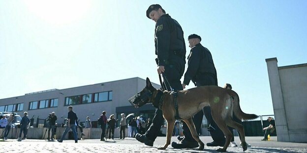 Zwei Polizisten und ein Hund vor einem Gerichtsgebäude