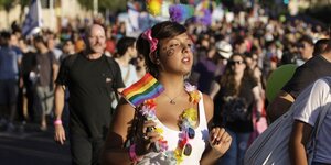 Menschen demonstrieren mit Ketten und Fahnen in Regenbogenfahnen