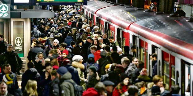 Menschen drängeln sich auf einem Bahnsteig vor den roten Waggons einer S-Bahn