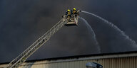 Feuerwehrleute auf einer Leiter löschen einen Brand