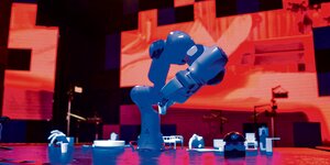 Ein Roboterarm auf einer rot beleuchteten Bühne.