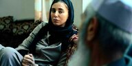 Die Journalistin Mariam Noori trägt ein Kopftuch und spricht mit ihrem Großvater auf einem Sofa