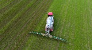 in Landwirt bringt mit seinem Gespann Gülle im sogenannten Schleppschuh Verfahren auf einem Feld aus