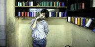 Ein Junge posiert für die Kamera vor Schränken mit Garnrollen