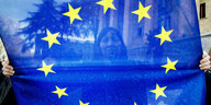 Eine Frau hält eine Fahne der EU in die Kamera