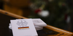 Vier Bücher mit dem Grundgesetz liegen während einer Einbürgerungsfeier auf einem Tisch im Ratssaal des Kieler Rathauses.