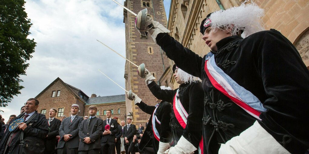 Burschenschaftler in Uniform stehen mit gezücken Degen im Innenhof der Wartburg in Eisenach.