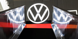 Eine Rolltreppe führt auf ein riesiger leuchtendes VW-Logo zu.