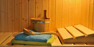 Ein Saunaraum mit Aufgusseimer, Holzkelle und Handtüchern
