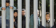 Geflüchtete in Bialowieza in Polen warten hinter einem Gitter