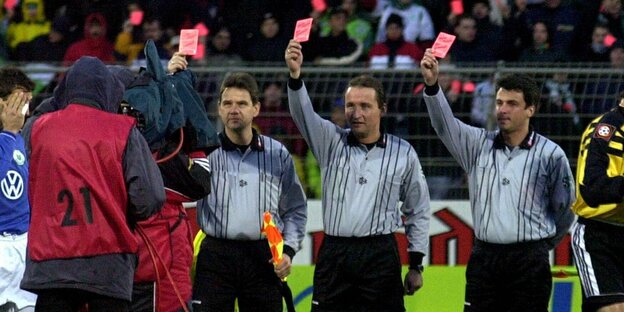 drei Schiedsrichter, die die Rote Karte in die Höhe strecken