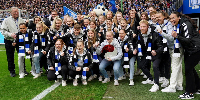 Frauen in schwarz-weiß-blauen Schals posieren für ein Gruppenfoto